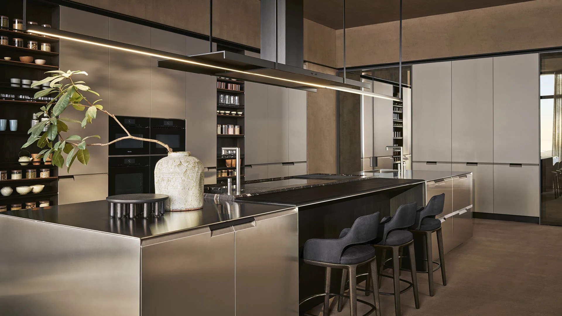 Cucina contemporanea con grande isola, superfici scure e sgabelli imbottiti