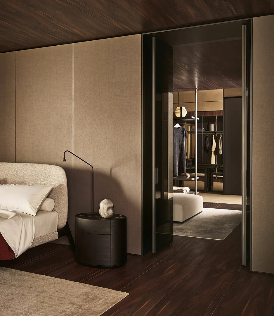 Letto con testiera imbottita e lampada da lettura davanti alla cabina armadio