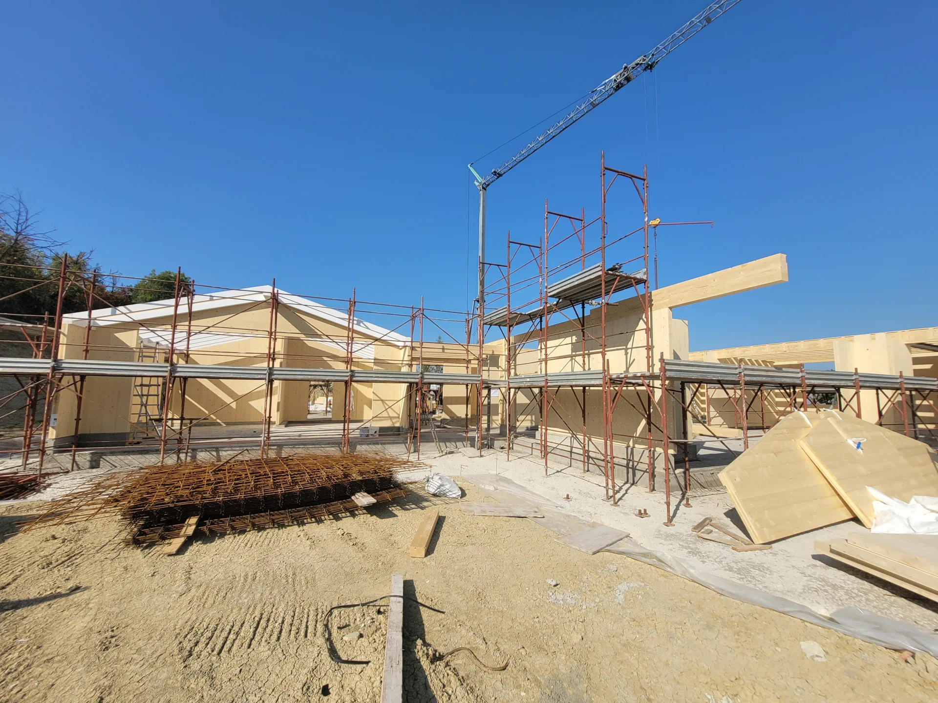 La struttura in legno tra i ponteggi e i materiali in attesa di posa.