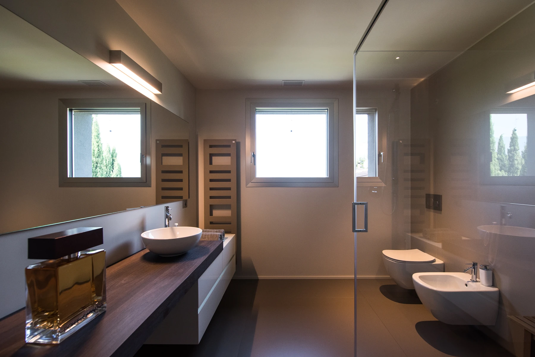 Bagno completo con lavabo in appoggio, mobile sospeso, vaso e bidet sospesi e doccia in vetro