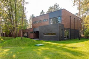 Casa contemporanea con rivestimento esterno in legno e grandi finestre nel verde