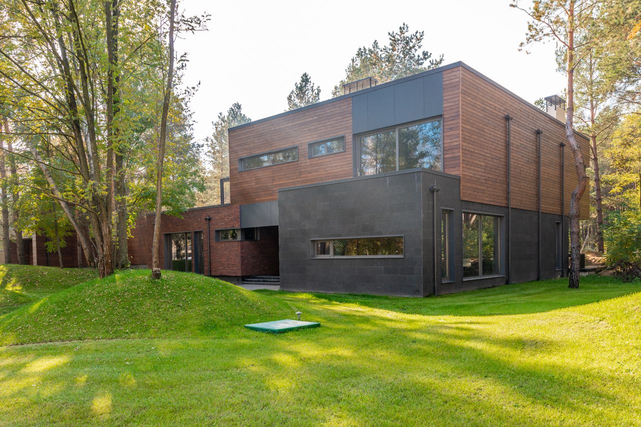 Casa contemporanea con rivestimento esterno in legno e grandi finestre nel verde