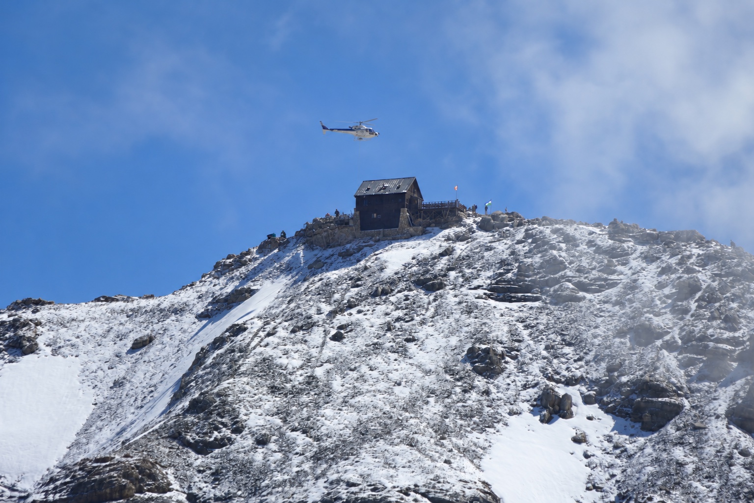 Elicottero sopra un rifugio su una cresta innevata